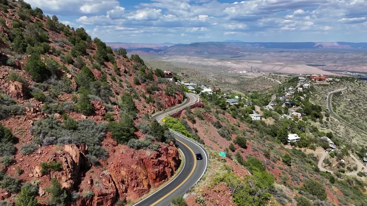 vista aérea de un coche conduciendo en una carretera de montaña con una curva aguda
