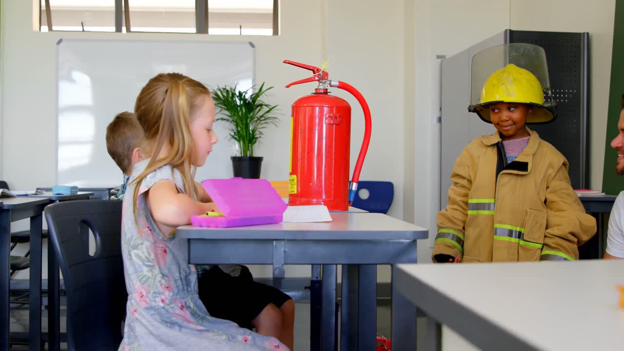 chico y chica caucásicos escuchando a un bombero caucásico y una chica afroamericana en la clase