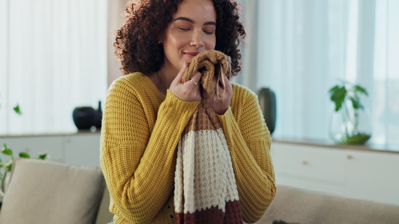 Woman smelling a cozy scarf at home