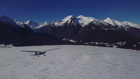 small plane flying over frozen mountain lake