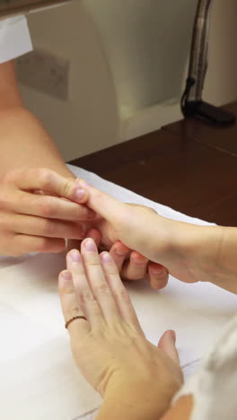 nail technician examining customers hands