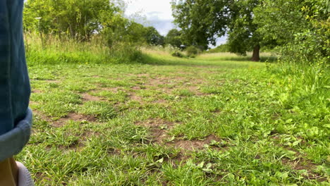 persona caminando con zapatos minimalistas descalzos en el campo de hierba, vista de bajo nivel