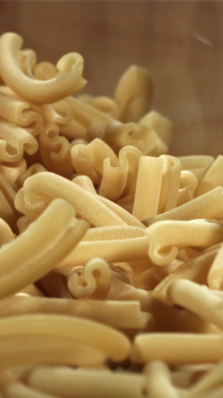 Primo piano di pasta secca che si riversa su una superficie di legno