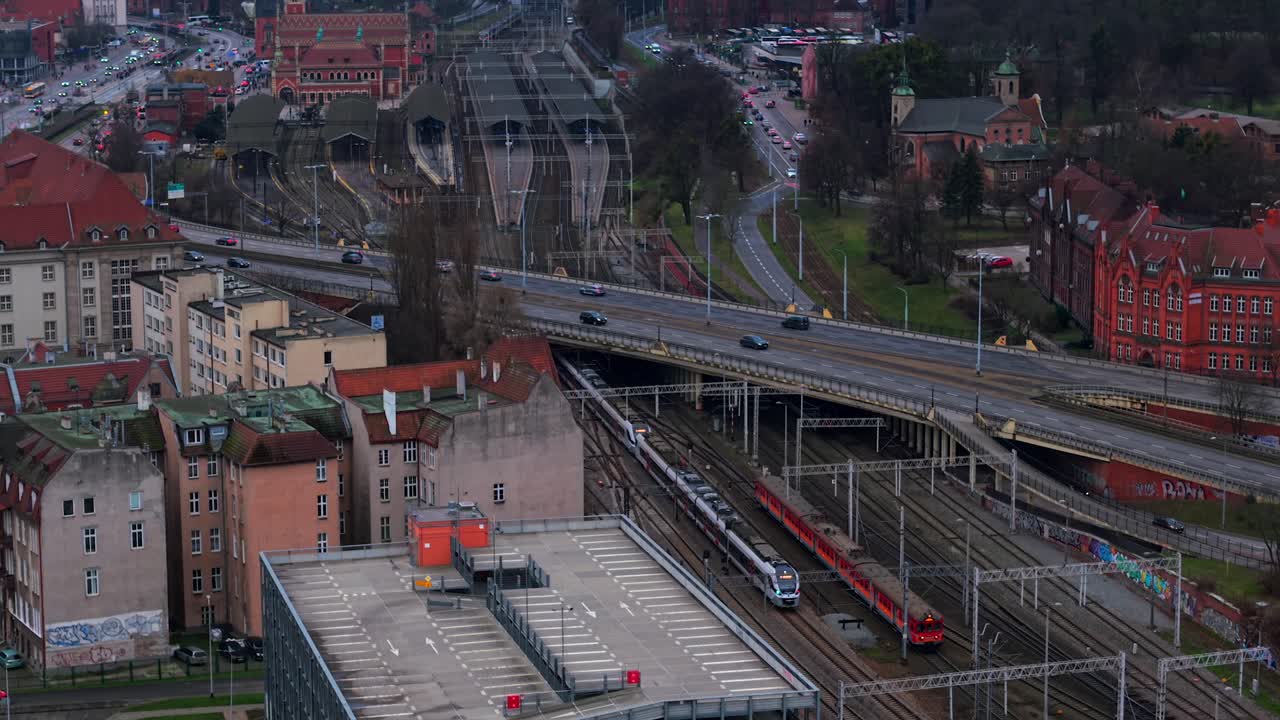 Aerial drone tracking two departing trains from Gdansk Glowny station, Poland, tracks leading into distance