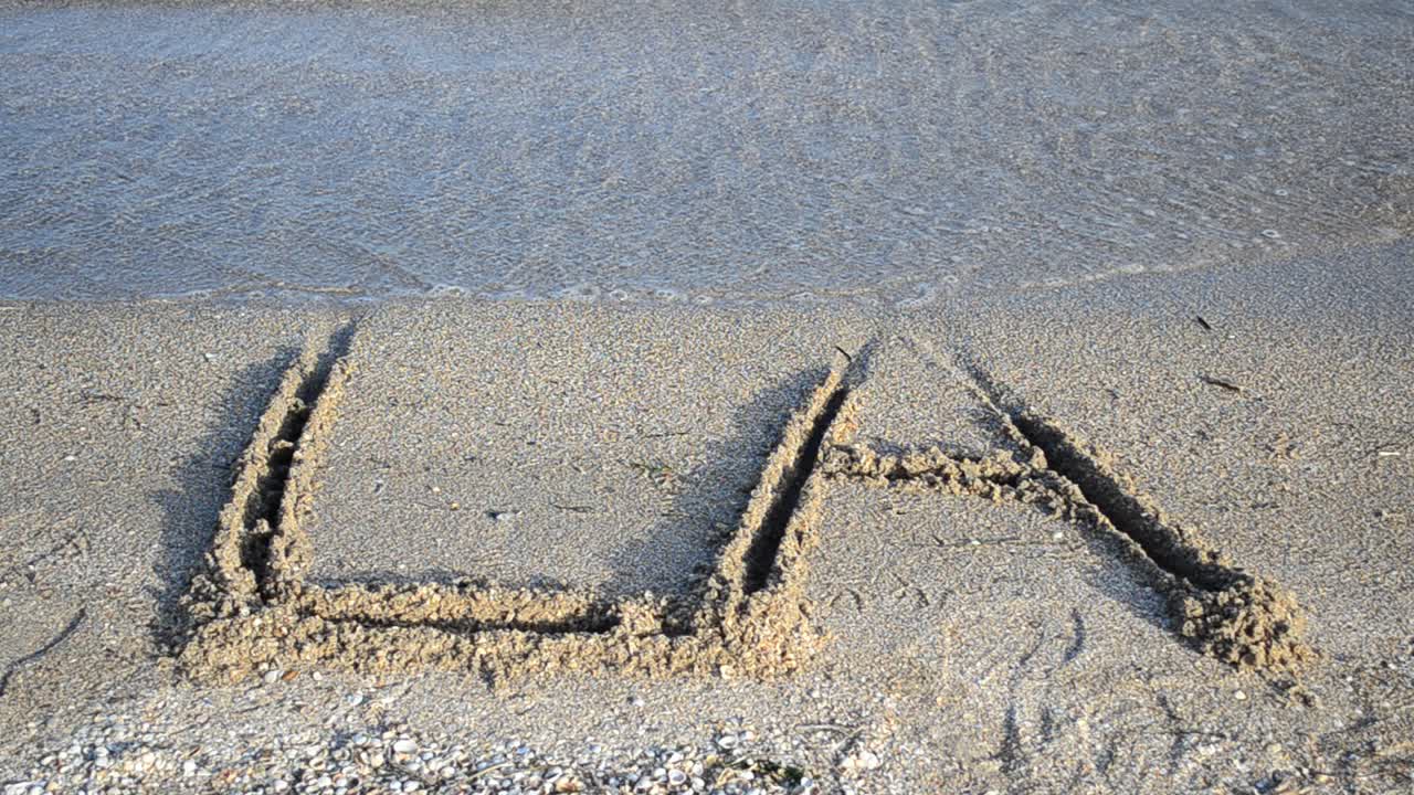 Inskripsjonen LA på sand. Inskripsjon på sand, stranden.