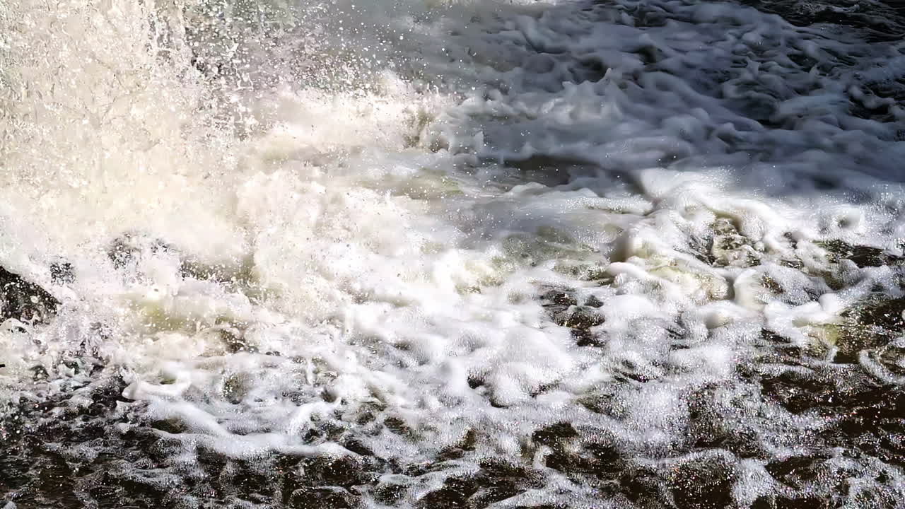 Splashing water at base of small waterfall with visible foam