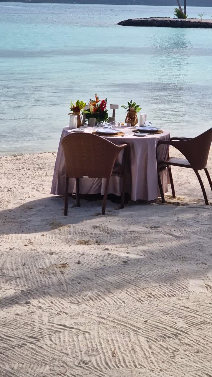 Bora Bora Island, French Polynesia. Vertical View of Dining Table For Two on Beach at Luxury Tropical Resort