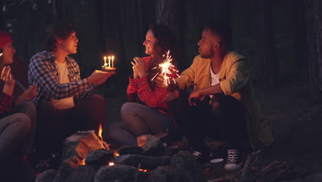 friends celebrating birthday around campfire