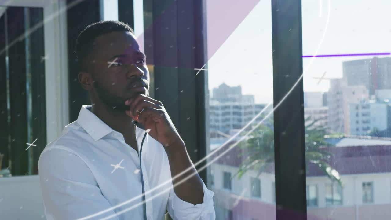 Animation of lines and circles over thoughtful african american man looking through window