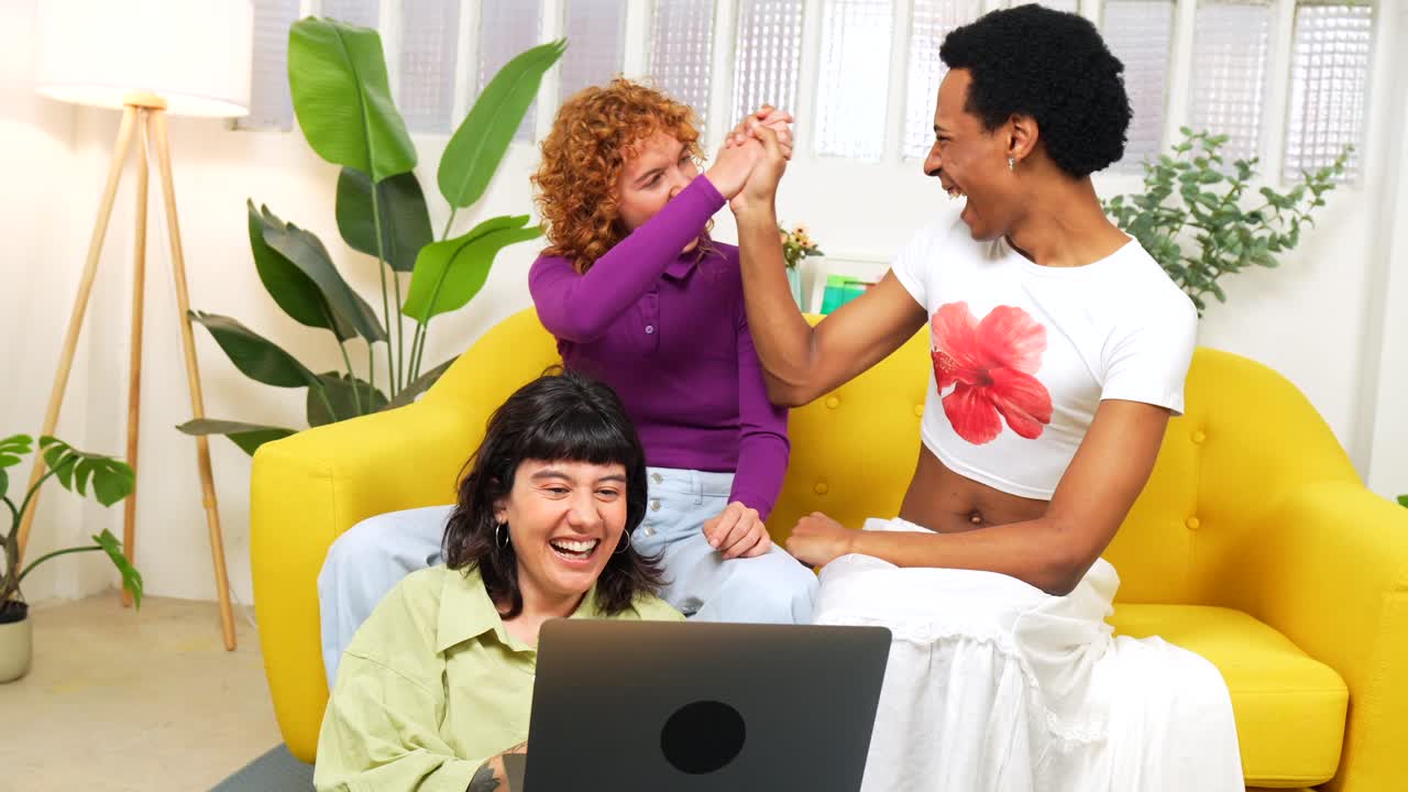 Friends laughing together while using a laptop indoors