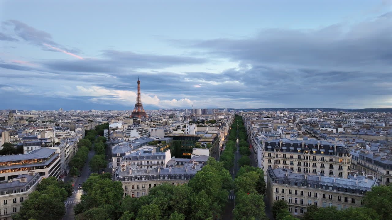 Distant view of the Eiffel Tower sparkling in the evening with buildings surrounding it in Paris, France