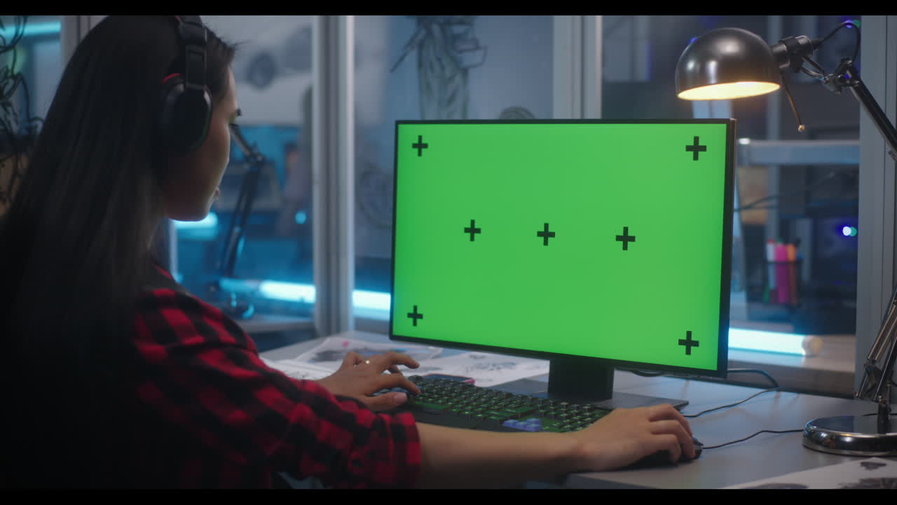 Woman working on a computer with a green screen