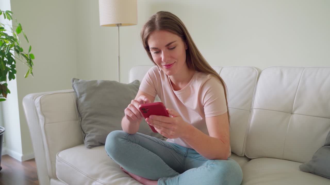 Young teenage woman in headphones using smartphone rest on sofa at home