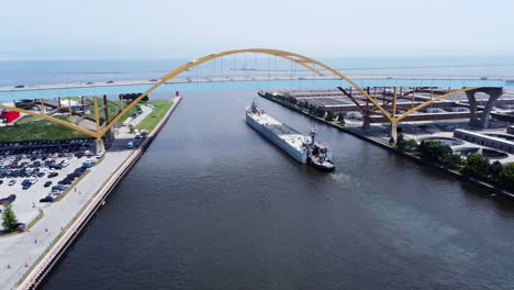 a large cargo ship going under a bridge in the downtown harbor of milwaukee, wisconsin