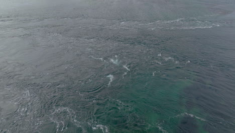 natural pattern of strong current forms small whirlpools in ocean surface, aerial orbiting