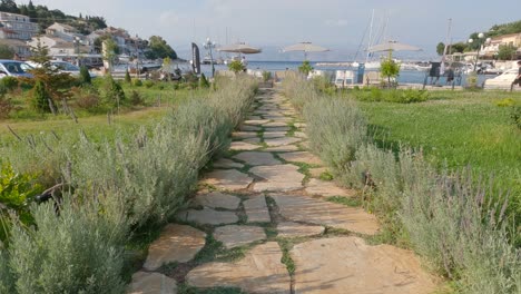 tiro inclinado desde el jardín rústico que conduce al paseo marítimo con sombrillas en kassiopi, corfú