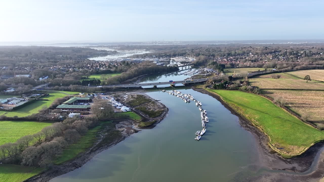 Ripresa aerea in volo verso il fiume Hamble e il cantiere navale di Hamble, ponti e autostrada nel Regno Unito soleggiato