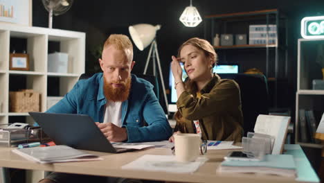 Young-female-and-male-professional-discussing-project-in-night-office