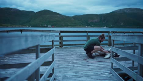 Man-Walks-Towards-Alaskan-Malamute-Pet-Dog-On-Boardwalk-And-Do-Belly-Rub