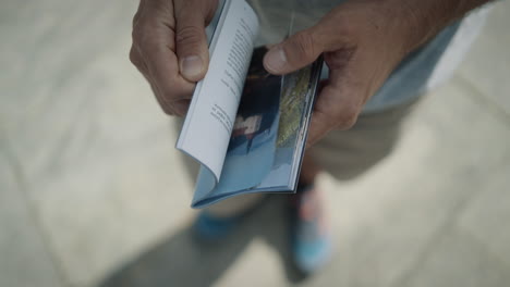 hombre que sostiene en sus manos un folleto y lo hojea en busca de datos interesantes sobre la ciudad