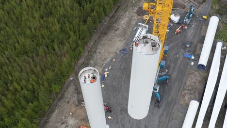 Proceso-De-Elevación-De-Una-Parte-De-La-Torre-De-Un-Generador-De-Energía-De-Turbina-Eólica,-Vista-De-ángulo-Alto