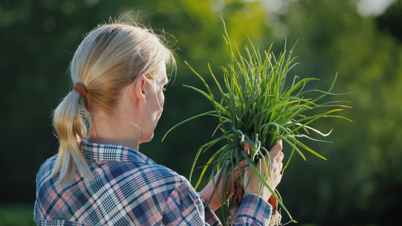 그녀의 손에 유기농 농업 개념에 녹색 양파와 여성 농부의 뒷모습