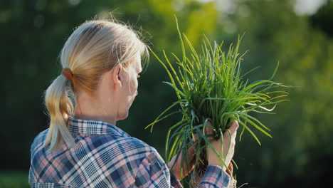 back view of a female farmer with a green onion in her hands organic farming concept