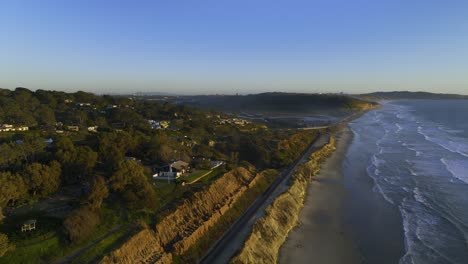 ascending aerial view tracking railroad tracks on the coast of san diego, hazy morning in california, usa