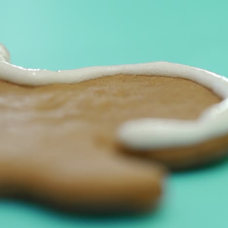 a confectioner is drawing a contour on ginger biscuits by white icing with using a confectionary nozzle for christmas. ginger man. sweets. close-up