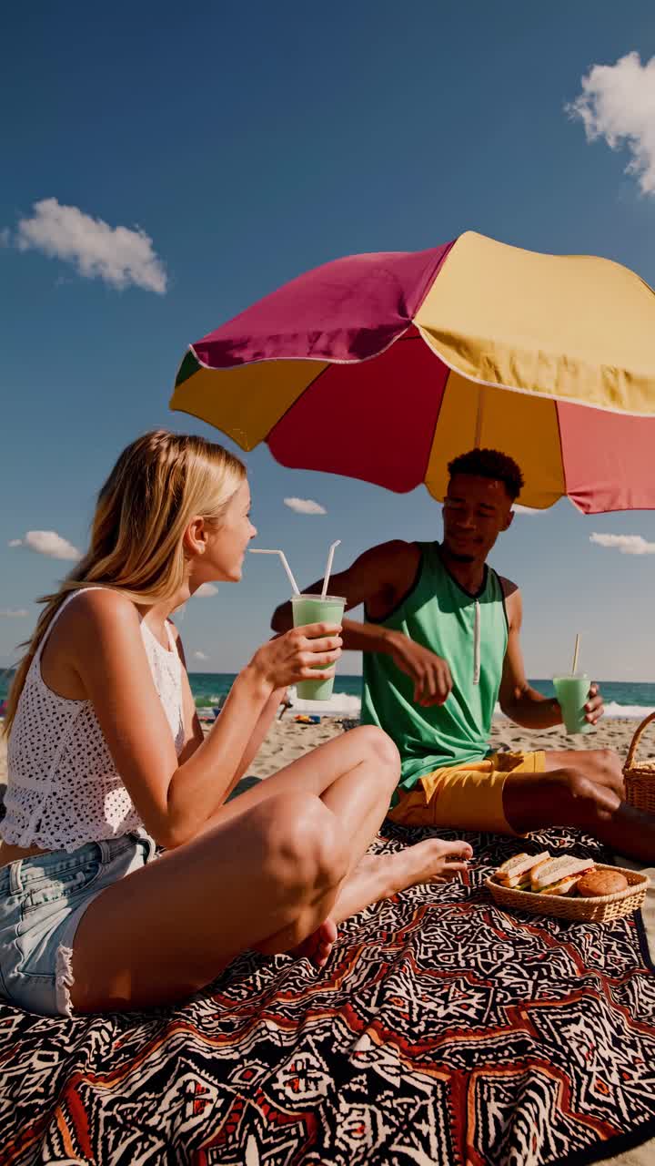 Un video ripreso da un'angolazione bassa mostra persone che si godono una giornata di sole in spiaggia, con cieli sereni e nuvole sparse.