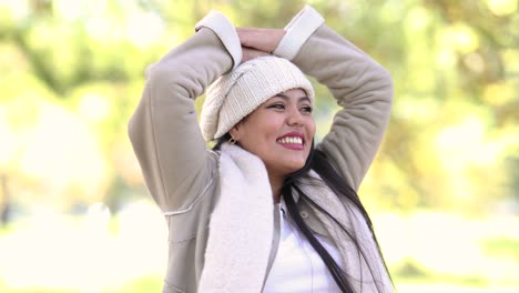 girl dressed warmly during the autumn fall season raises her hands in complete bliss and happiness at a park