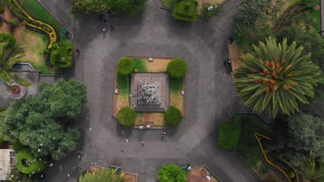 Aerial-Pull-Out-Drone-Shot-Over-Juan-Montalvo-Statue-with-a-Flock-of-Birds-Flying-Below