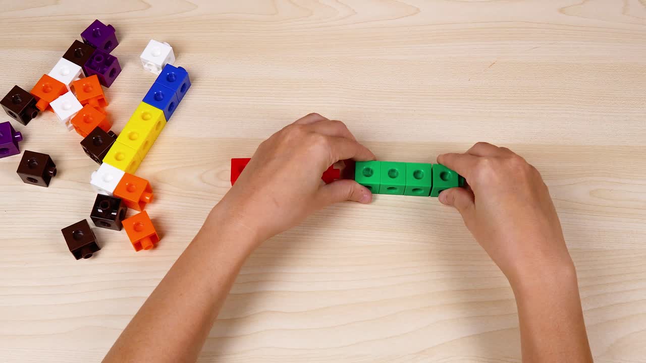 manos montando cubos verdes en una mesa de madera