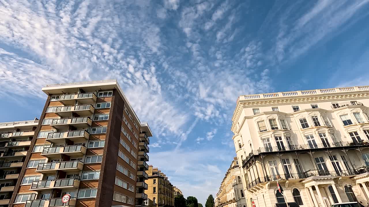 Auto che passano davanti a edifici sotto un cielo azzurro