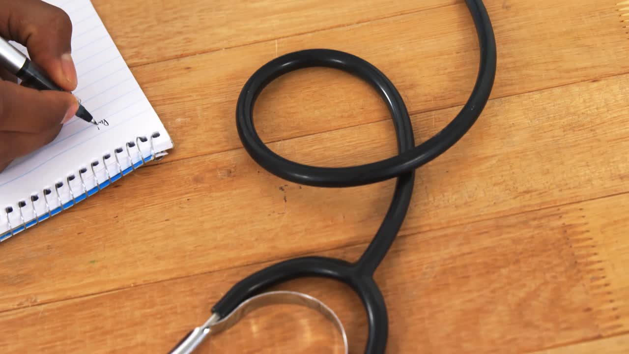 le médecin écrit sur son bloc-notes à son bureau.