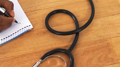 doctor writing on notepad at his desk