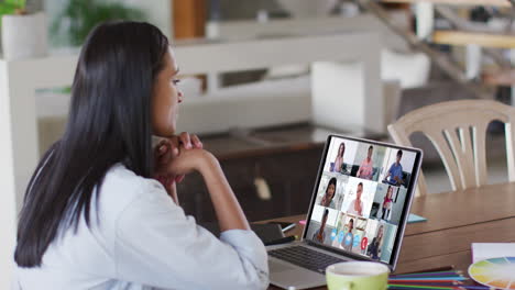 mujer caucásica usando una computadora portátil en una videollamada con colegas que trabajan desde casa