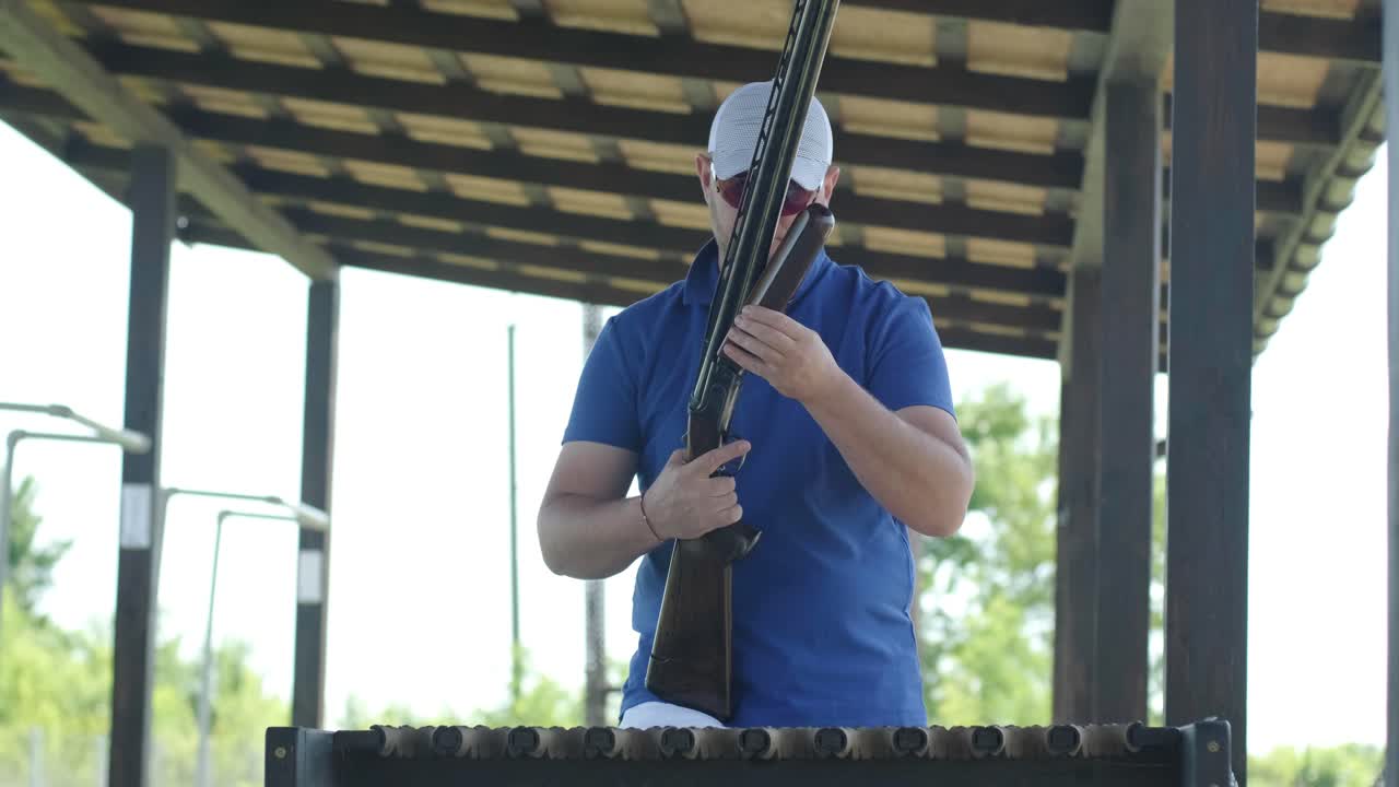 스포츠맨이 이중 배럴 건으로 총을 고, 슈팅 테스트를 위한 스포츠 경기장은 날아다니는 스케이트를 고 있습니다.