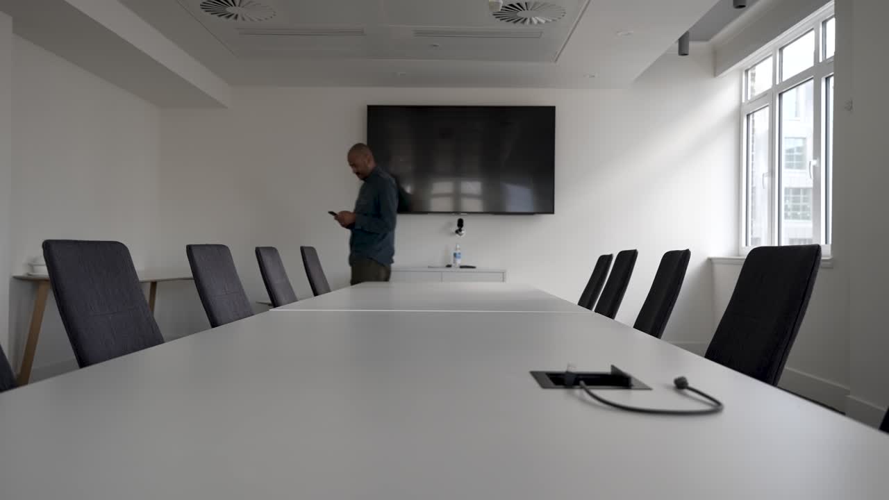 hombre de negocios impaciente mirando en el teléfono inteligente esperando invitados en la sala de reuniones