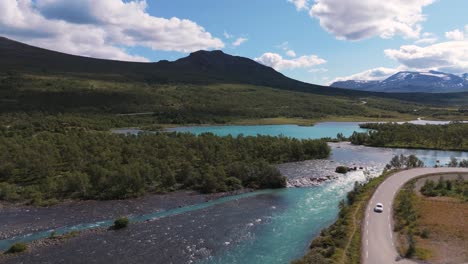 a stunning aerial view of the besseggen river winding through lush greenery with a scenic road in norway's innlandet region