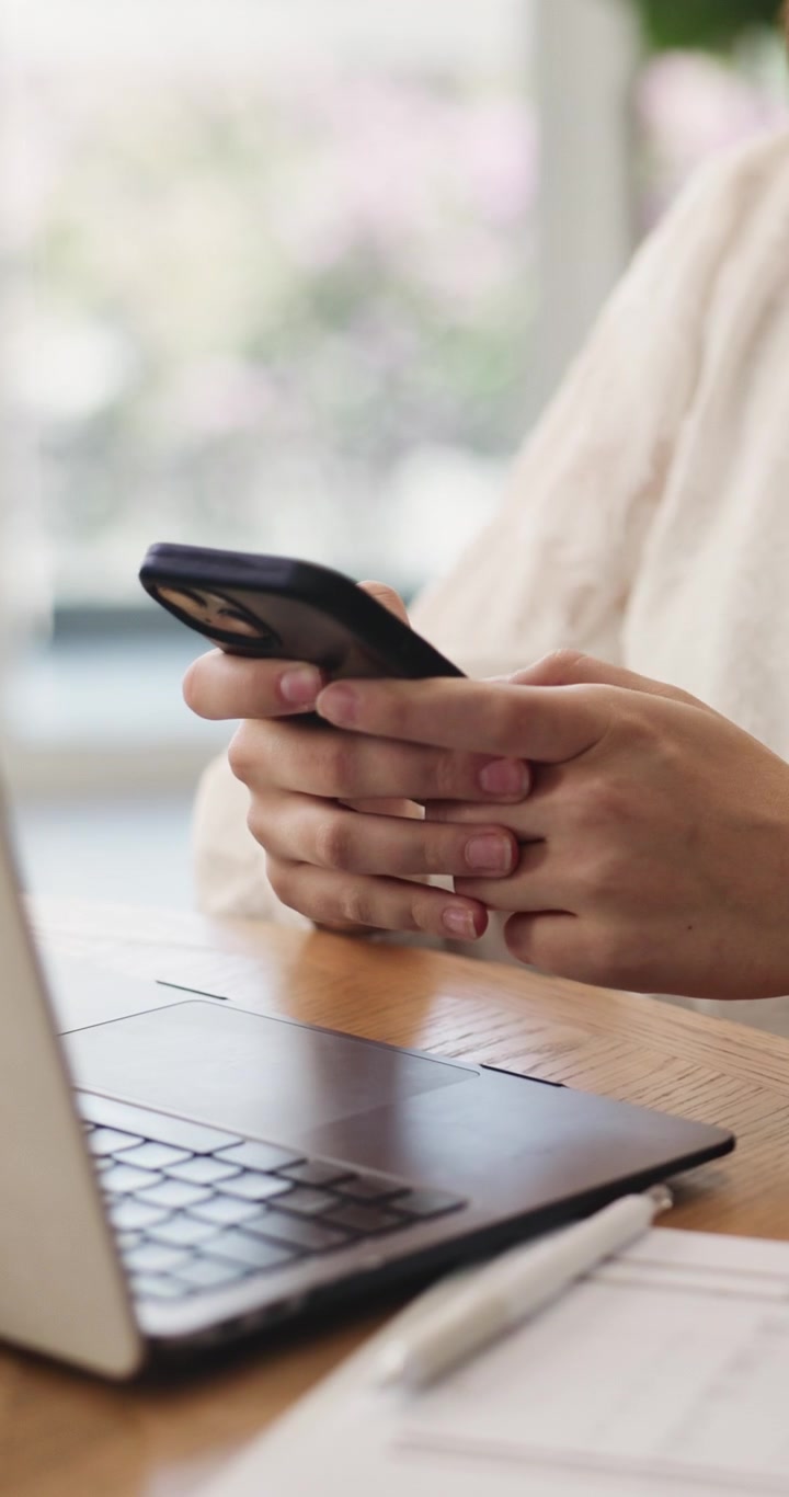 Donna che usa lo smartphone mentre lavora alla scrivania