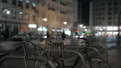 Geparkte-Fahrräder-Vor-Der-Verschwommenen-Nacht-Der-Stadt