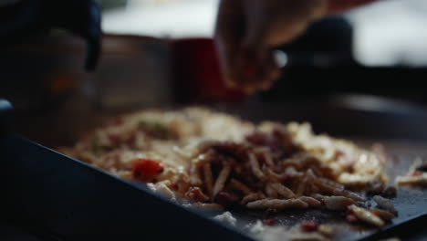 Seasoning-steaming-potato-noodle-dish-with-ripped-cooking-gloves