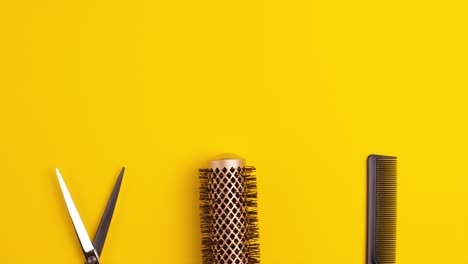 stop motion animation template flat lay of professional hair cutting shears comb for separating hair and gold round hair brush for styling on yellow background hairdresser salon equipment concept