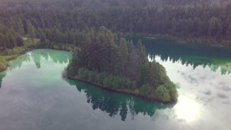 Península-Del-Lago-Espejo-Turquesa-Claro-Con-Reflejos-De-Nubes-Y-Pinos