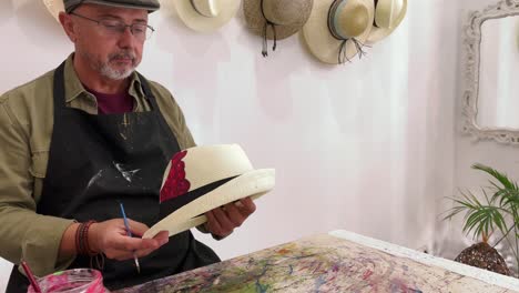 Talented-male-artist-painting-on-hat-in-creative-studio