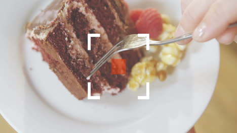 Cutting slice of cake with berries and popcorn using fork on plate