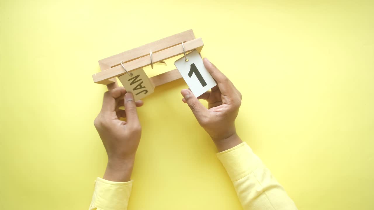 manos ajustando un calendario de madera al 1 de enero