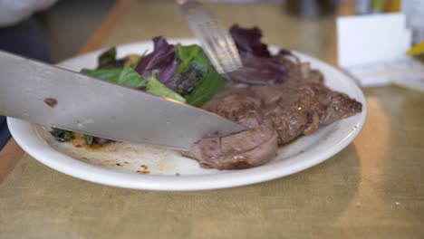 cortar un bistec en un plato con ensalada verde