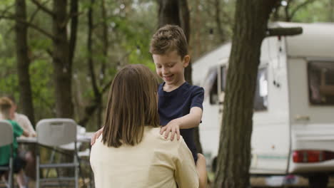 loving mother crouching and talking to her cute son who listening attentively at the camping in the forest